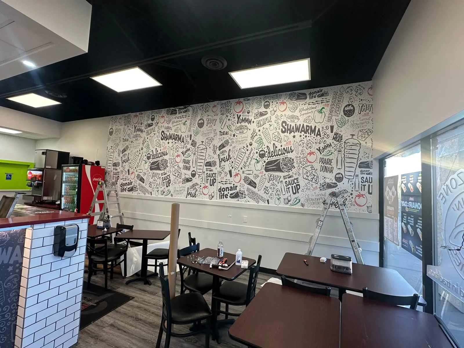 Black and white doodle wall mural installed in a shawarma dining room
