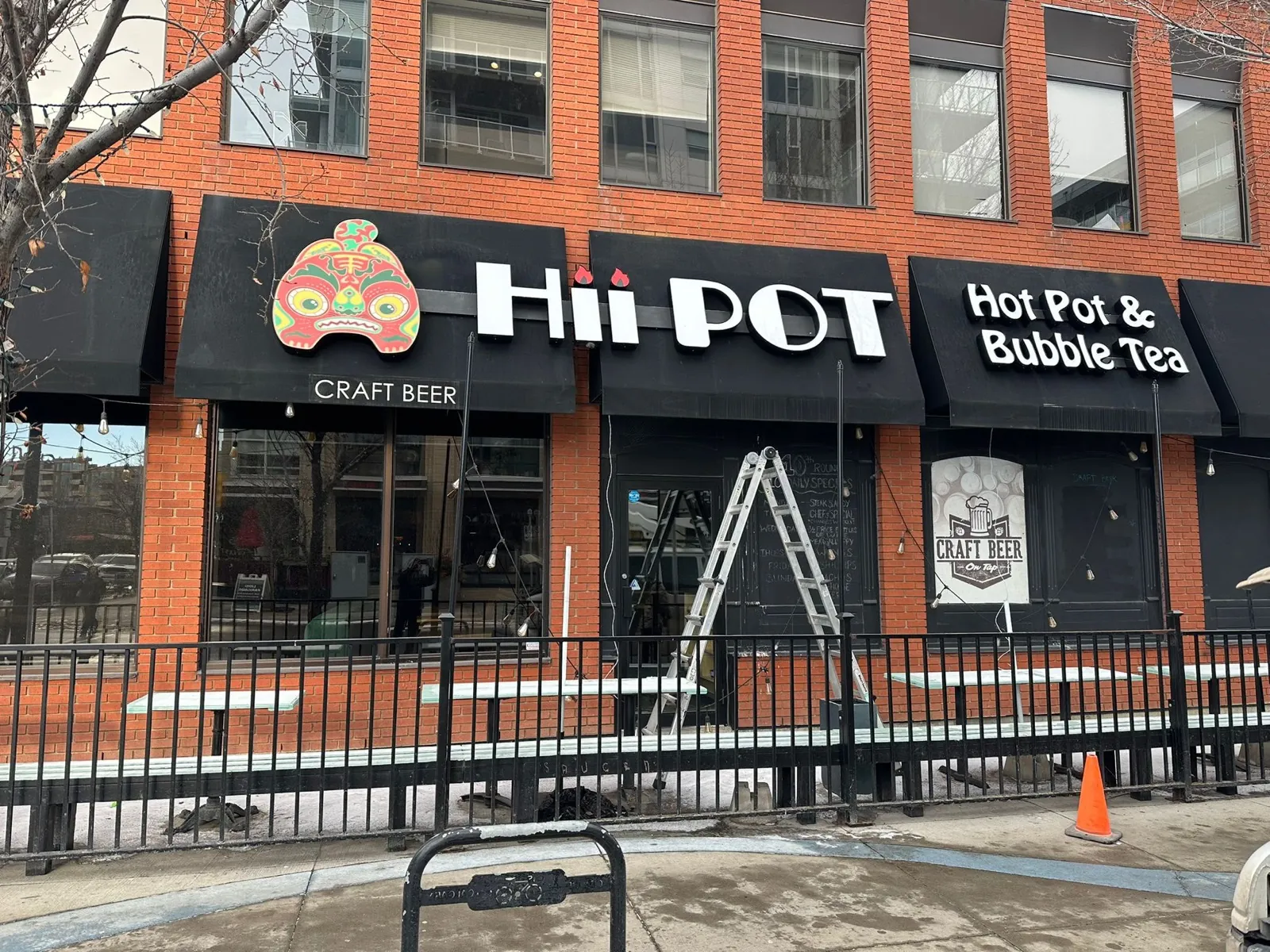Hii Pot white channel letters and mask logo on black awnings over a brick facade