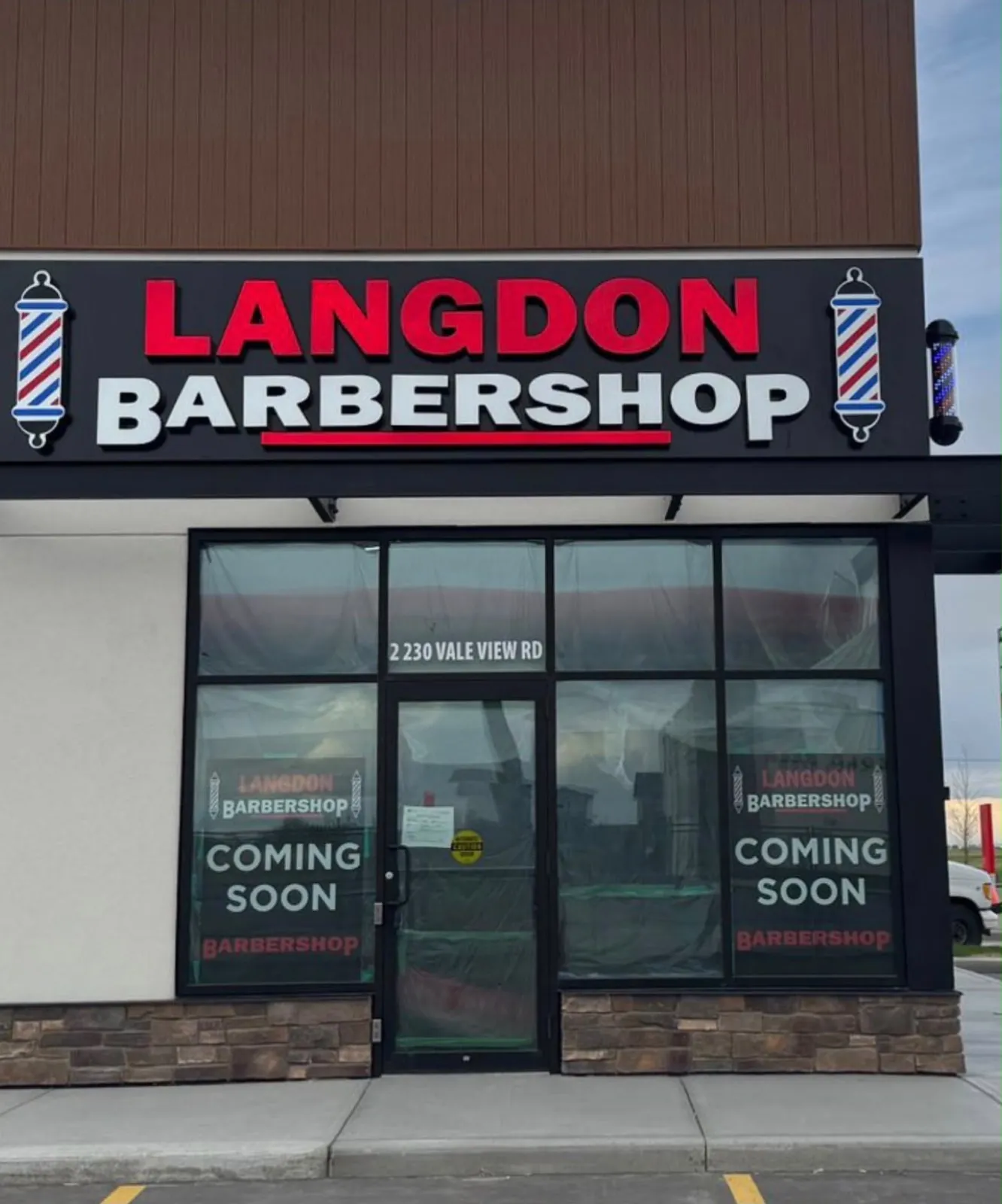 Langdon Barbershop illuminated sign with barber pole graphics above the finished storefront