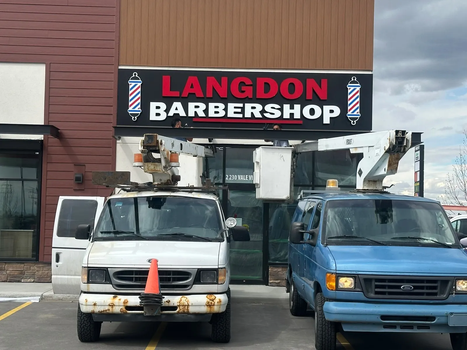 Bucket trucks installing the Langdon Barbershop illuminated sign