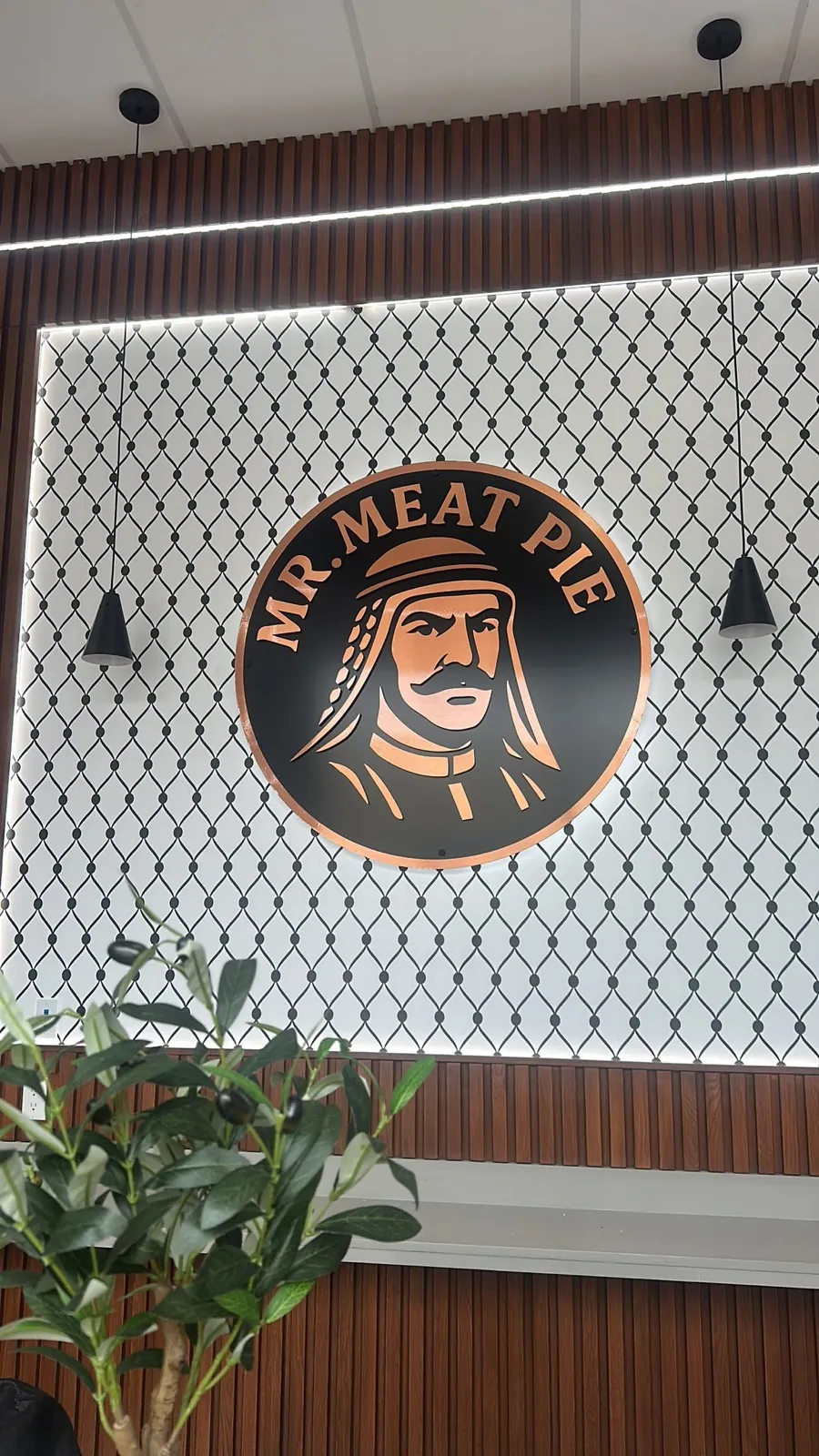 Mr. Meat Pie round logo mounted on a keffiyeh patterned feature wall