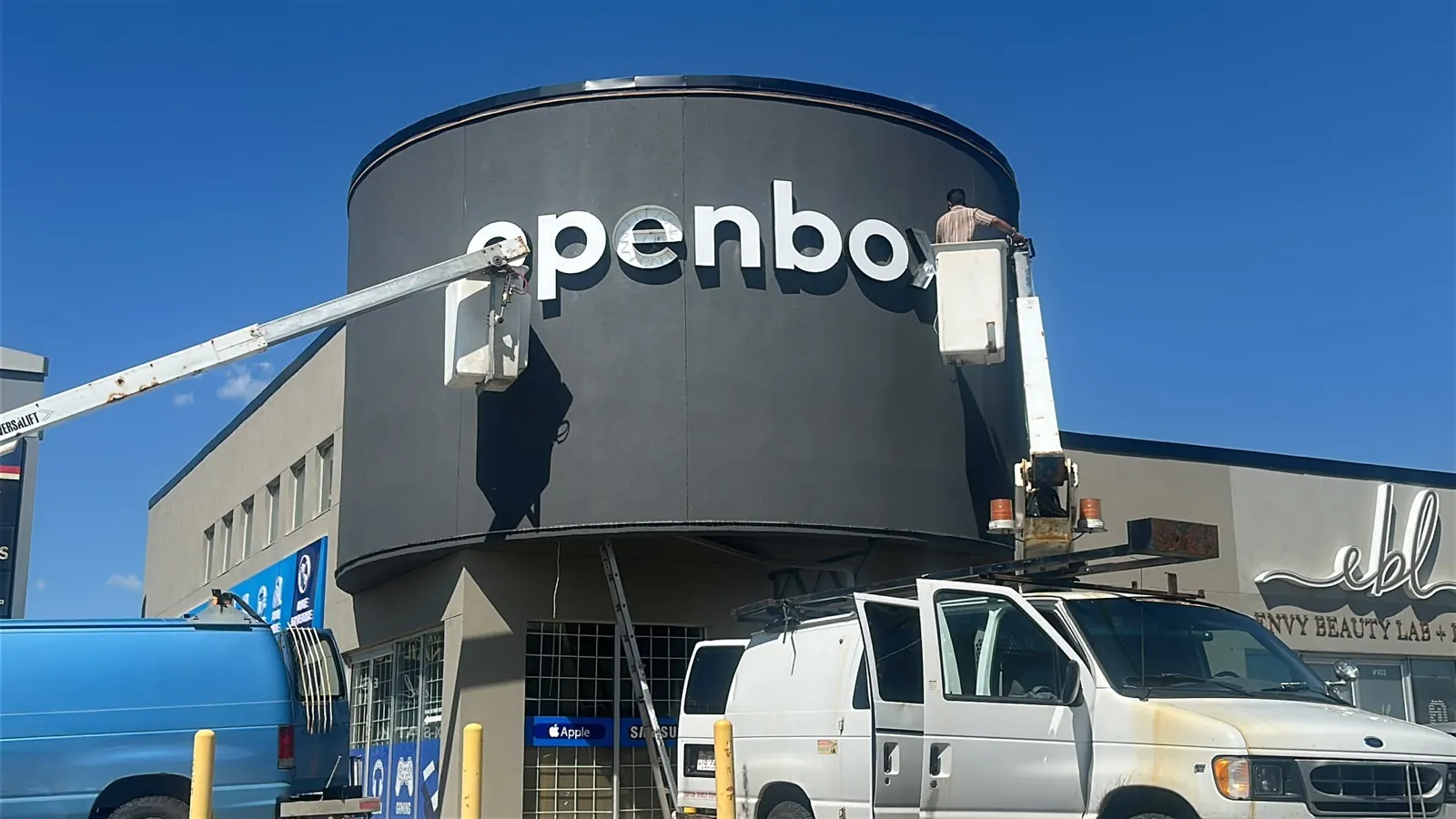 Crews on bucket lifts installing the Openbox tower letters