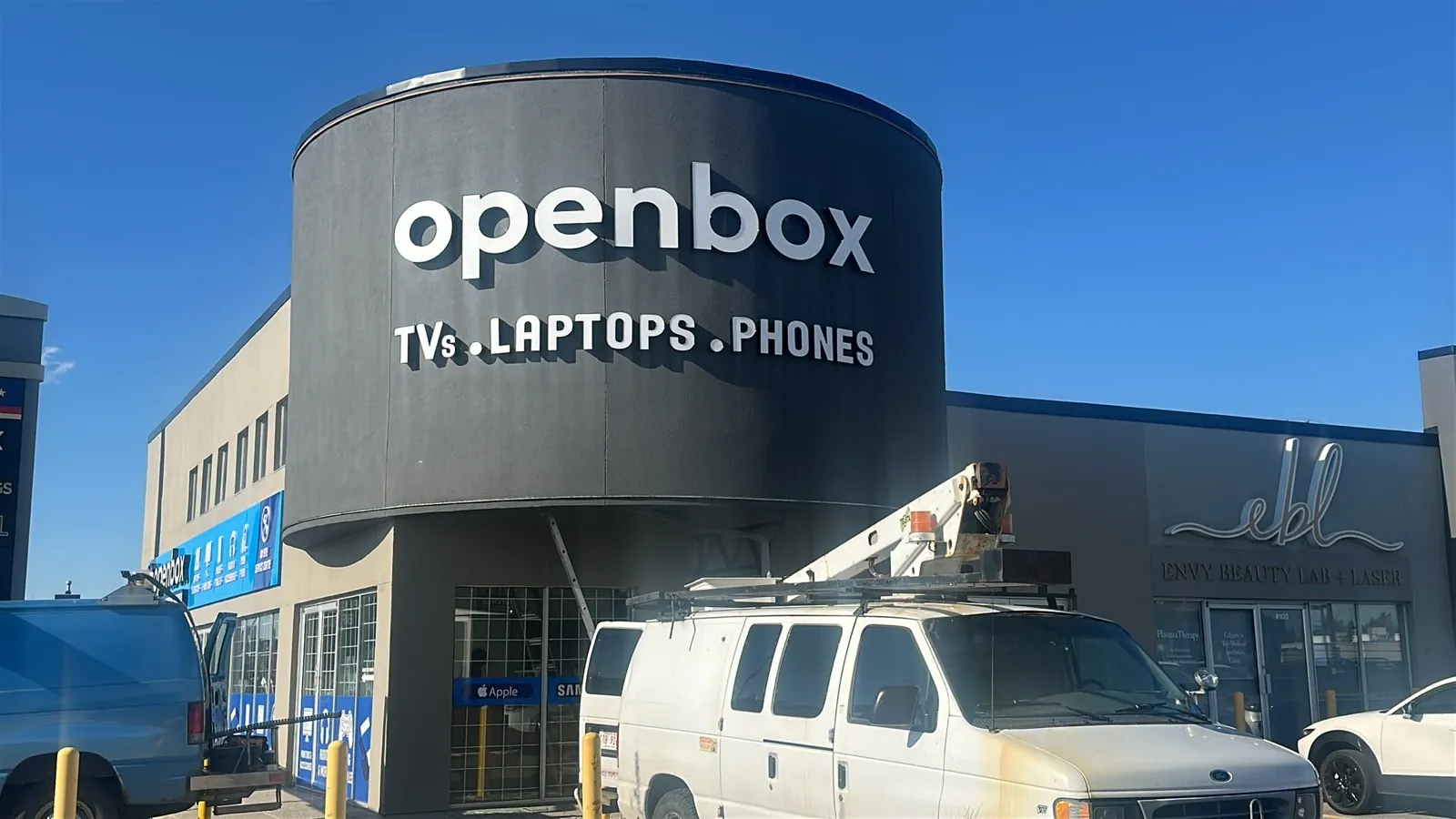 Openbox TVs laptops phones white dimensional letters wrapping a round black tower