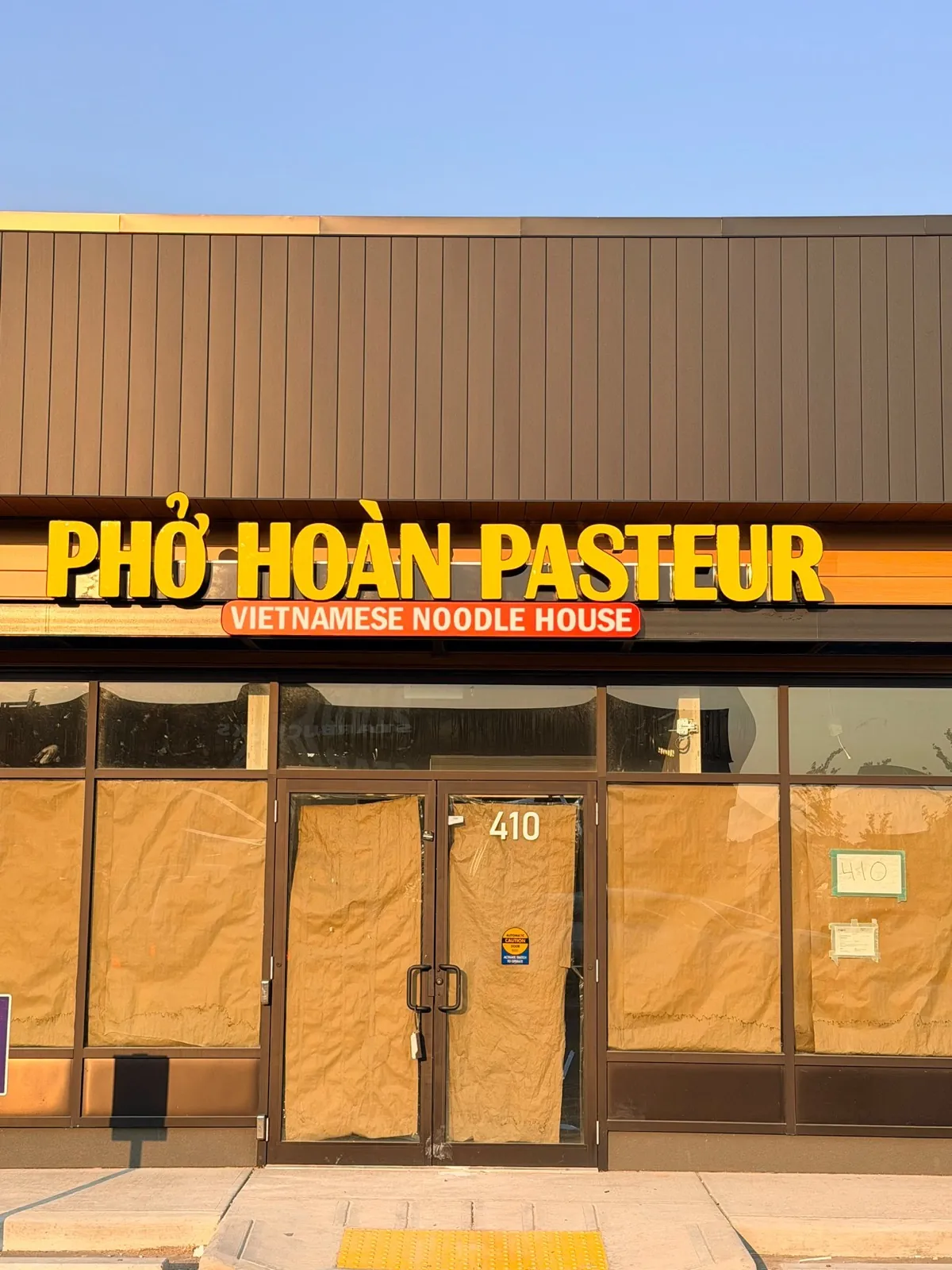 Pho Hoan Pasteur yellow channel letters over a papered storefront before opening